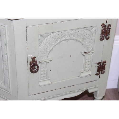 101 - A vintage side cupboard of trapezium form with carved details and a vintage metal travelling trunk, ... 