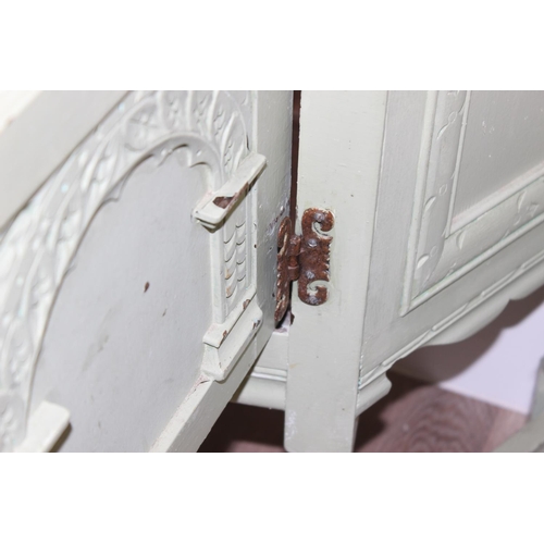 101 - A vintage side cupboard of trapezium form with carved details and a vintage metal travelling trunk, ... 