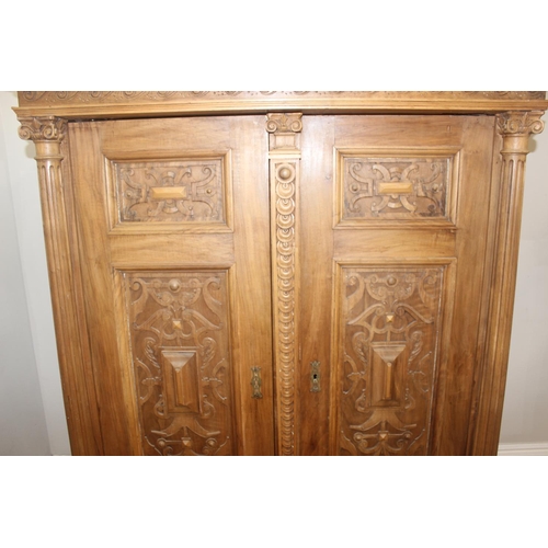 30 - A large impressive antique wardrobe with profusely carved details and ionic column supports, 2 doors... 