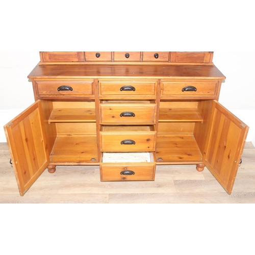 26 - A modern pine dresser, the base with 4 central drawers flanked by a drawer over a cupboard, the top ... 