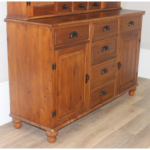 26 - A modern pine dresser, the base with 4 central drawers flanked by a drawer over a cupboard, the top ... 