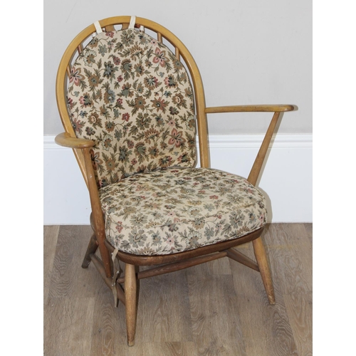 12 - Ercol - a retro low backed armchair with mid-century floral cushions, fleur-de-lys slat back, light ... 