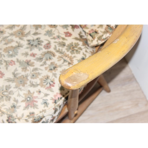 12 - Ercol - a retro low backed armchair with mid-century floral cushions, fleur-de-lys slat back, light ... 