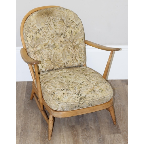 9 - Ercol - a retro low backed armchair with mid-century floral cushions, believed to be a model 334 fro... 