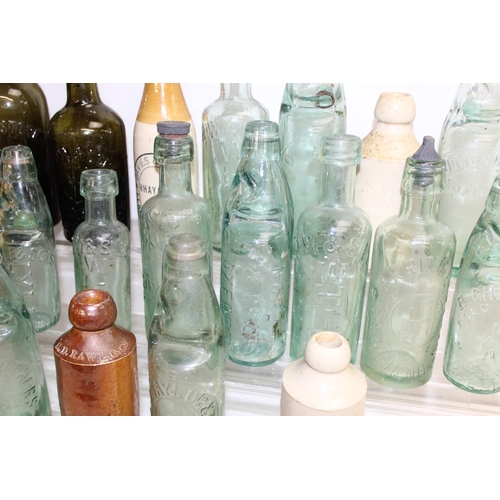 1657 - Qty of assorted antique and later glass and pottery bottles, many advertising, and some with local i... 