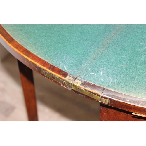 93 - A Victorian mahogany demi-lune card table with fold over top and green baize lined interior, approx ... 