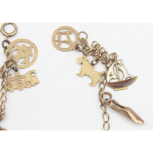 1154 - A vintage 9ct gold charm bracelet with a number of 9ct gold charms, some with enamel, to include tra... 