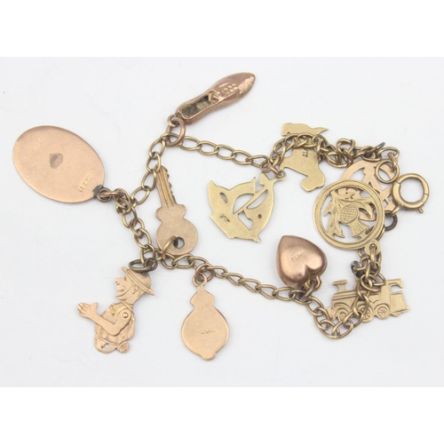 1154 - A vintage 9ct gold charm bracelet with a number of 9ct gold charms, some with enamel, to include tra... 