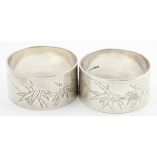 1075 - A pair of heavy gauge silver napkin ring with engraved bamboo design, named Rosemary & Michael, mark... 