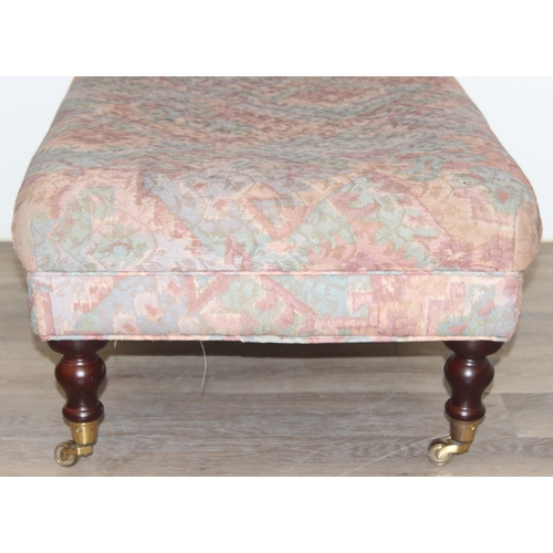 89 - An antique style ottoman or footstool with turned wooden legs and brass castors, approx 95cm wide x ... 