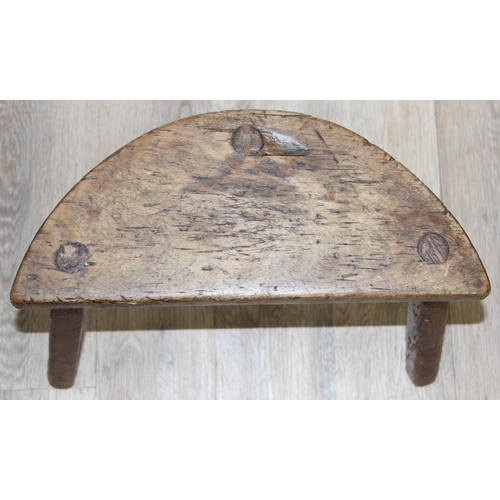 39 - An unusual demi-lune shaped elm milking stool with 3 legs, possibly the base of a Welsh yoke back ch... 