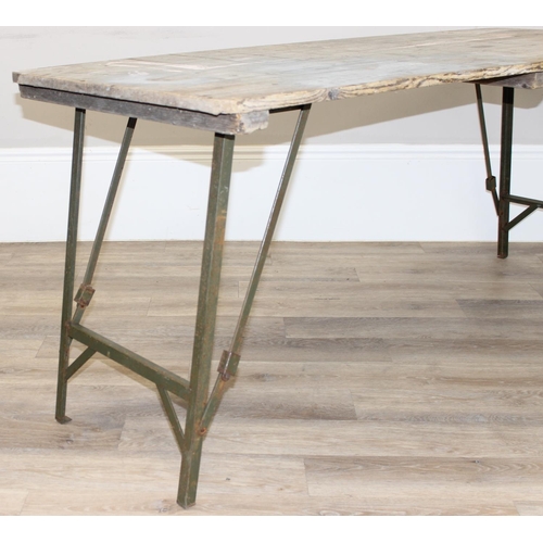 108A - A vintage weathered pine trestle table with folding metal legs, military markings to base and dated ... 