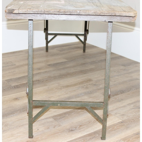 108A - A vintage weathered pine trestle table with folding metal legs, military markings to base and dated ... 