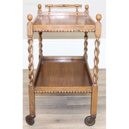 78 - A vintage oak serving trolley with barley-twist supports and wheels, approx 83cm wide x 46cm deep x ... 