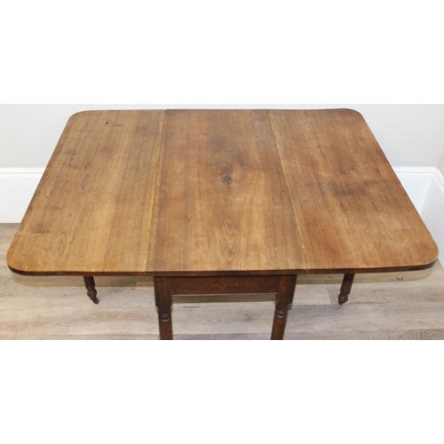 119 - An antique mahogany drop leaf table with turned legs and brass and ceramic castors, approx 100cm wid... 