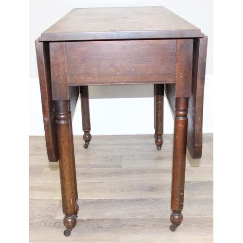 119 - An antique mahogany drop leaf table with turned legs and brass and ceramic castors, approx 100cm wid... 