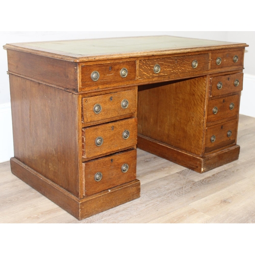 82 - An antique oak 9 drawer pedestal desk with green inset leather top and brass ring handles, early 20t... 