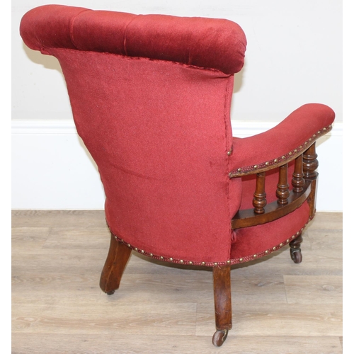 86 - A 19th century red button backed low armchair or library chair with turned wooden legs and scroll ba... 