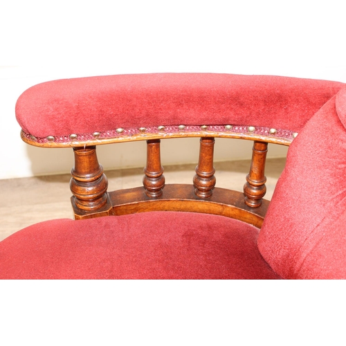 86 - A 19th century red button backed low armchair or library chair with turned wooden legs and scroll ba... 