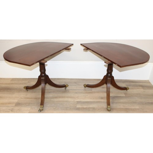 51 - An antique style mahogany twin pedestal dining table with extensions and brass lion paw castors, app... 