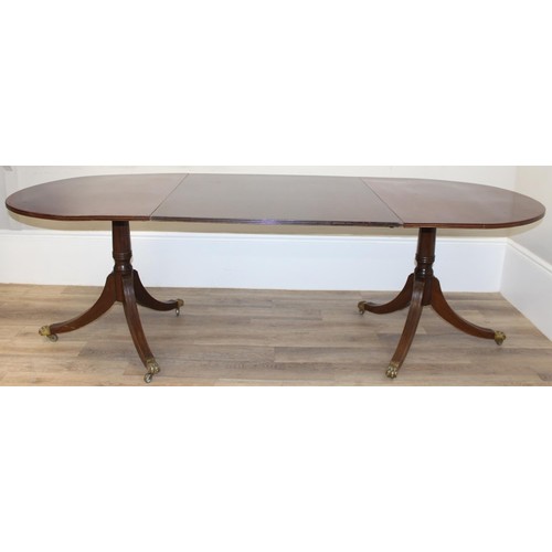 51 - An antique style mahogany twin pedestal dining table with extensions and brass lion paw castors, app... 