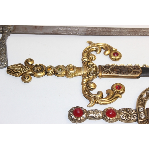 1413 - An Indian brass-hilted sword in red velvet scabbard, two Spanish tourist type large and small decora... 