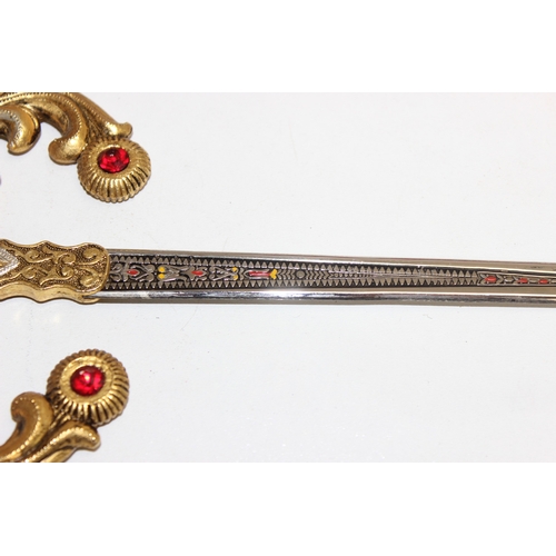 1413 - An Indian brass-hilted sword in red velvet scabbard, two Spanish tourist type large and small decora... 