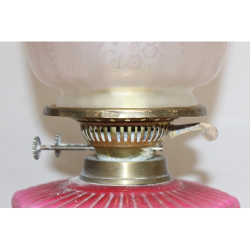 232 - An antique oil lamp with acid etched shade, a moulded pink glass reservoir, brass column and black b... 