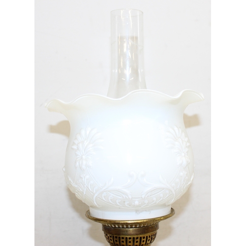 234 - An antique oil lamp with moulded milk glass shade, a glass reservoir, and an embossed brass base, ma... 