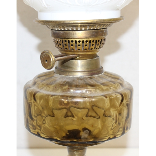 234 - An antique oil lamp with moulded milk glass shade, a glass reservoir, and an embossed brass base, ma... 