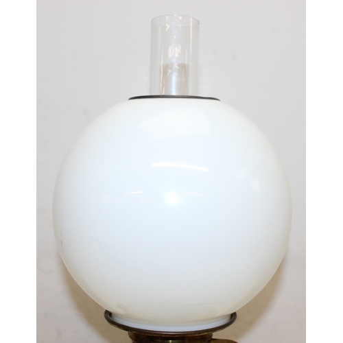 238 - An antique oil lamp with globe shaped milk glass shade, an amber coloured glass reservoir, and a bla... 