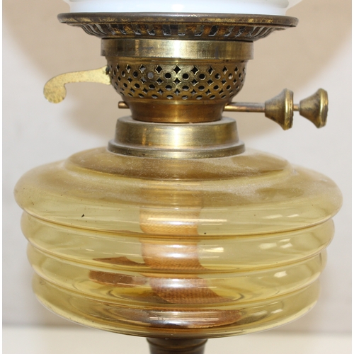 238 - An antique oil lamp with globe shaped milk glass shade, an amber coloured glass reservoir, and a bla... 