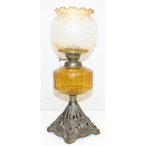 239 - An antique oil lamp with decorative glass shade, an amber coloured glass reservoir, and a cast iron ... 