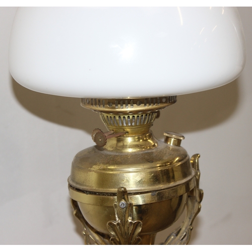 240 - An antique oil standard lamp with milk glass shade, a brass reservoir, and a telescopic brass base, ... 