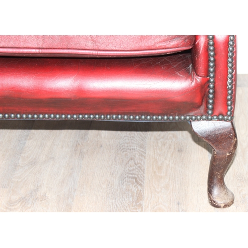 80 - An Ox-Blood red leather Chesterfield style wingback armchair by Wyvern, approx 82cm wide x 100cm tal... 