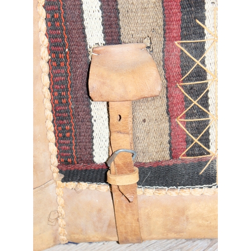 292 - Vintage leather and kilim fabric mounted saddle, possibly for a camel, with leather straps and stitc... 