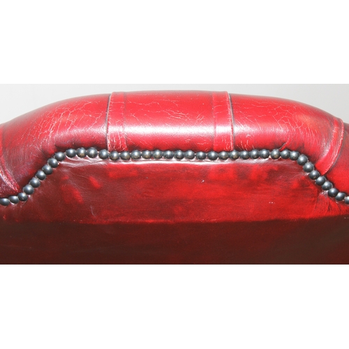 80 - An Ox-Blood red leather Chesterfield style wingback armchair by Wyvern, approx 82cm wide x 100cm tal... 