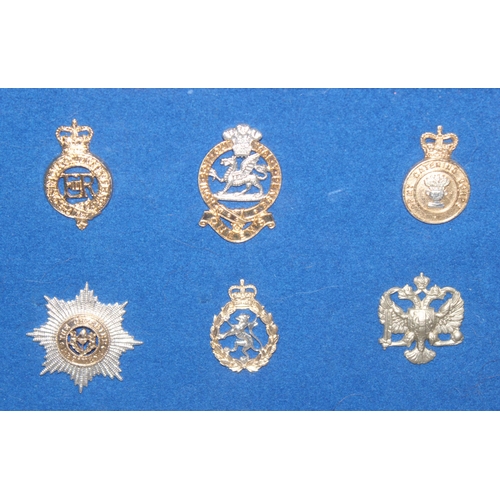 1444 - A set of vintage military cap badges presented in frame on blue felt background, mainly Staybrite ex... 