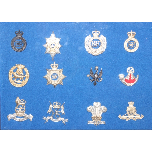 1444 - A set of vintage military cap badges presented in frame on blue felt background, mainly Staybrite ex... 