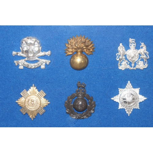 1444 - A set of vintage military cap badges presented in frame on blue felt background, mainly Staybrite ex... 