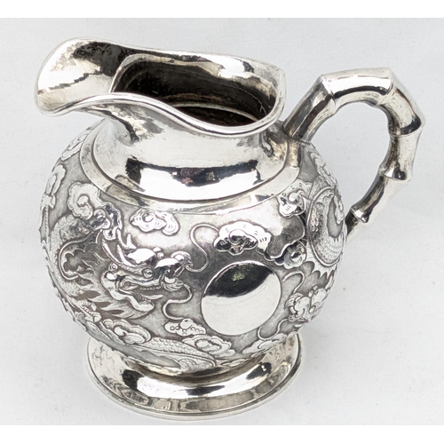 1124 - An impressive Chinese export silver cream or milk jug, embossed dragon design with bamboo effect han... 