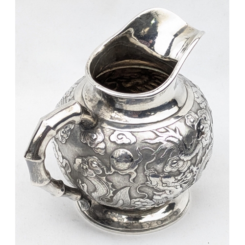 1124 - An impressive Chinese export silver cream or milk jug, embossed dragon design with bamboo effect han... 