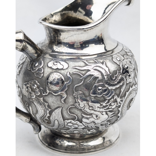 1124 - An impressive Chinese export silver cream or milk jug, embossed dragon design with bamboo effect han... 