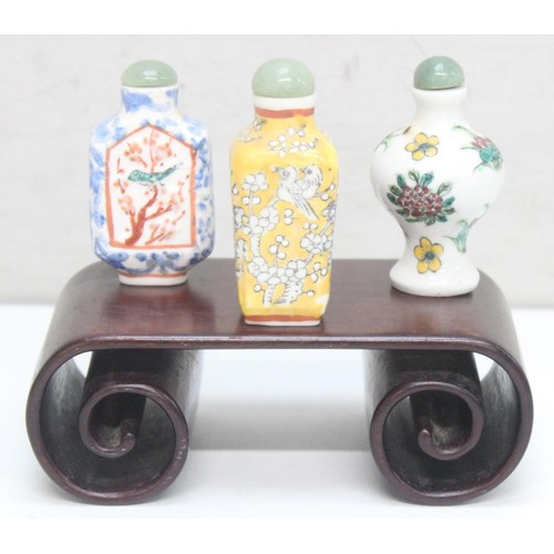 1687 - 3 assorted Chinese porcelain snuff bottles on wooden stand, all with polychrome decoration, the larg... 