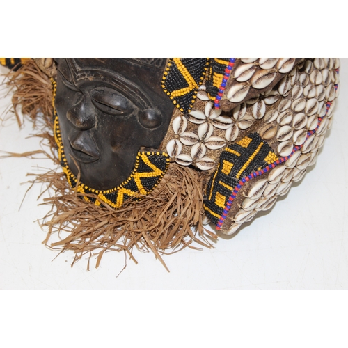 1528 - A vintage African carved wooden mask decorated with beadwork and cowrie shells, possibly a Congolese... 