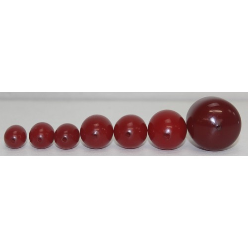 1175 - A qty of assorted loose beads, believed to be cherry amber Bakelite, the largest bead approx 45mm wi... 