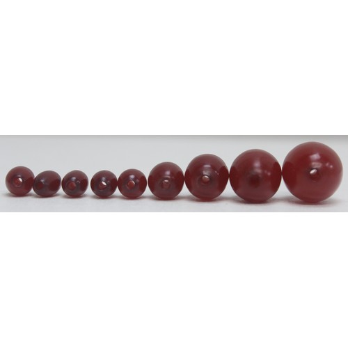 1175 - A qty of assorted loose beads, believed to be cherry amber Bakelite, the largest bead approx 45mm wi... 