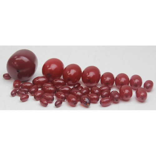 1175 - A qty of assorted loose beads, believed to be cherry amber Bakelite, the largest bead approx 45mm wi... 