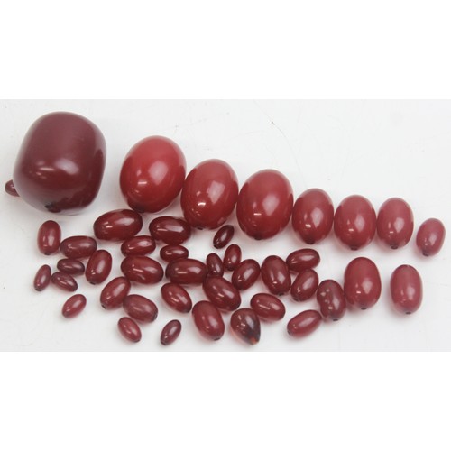 1175 - A qty of assorted loose beads, believed to be cherry amber Bakelite, the largest bead approx 45mm wi... 