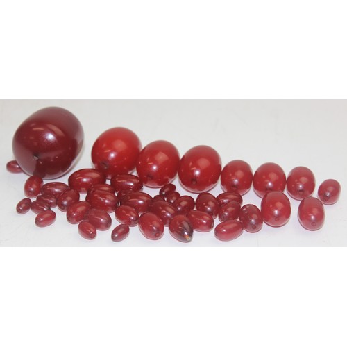 1175 - A qty of assorted loose beads, believed to be cherry amber Bakelite, the largest bead approx 45mm wi... 